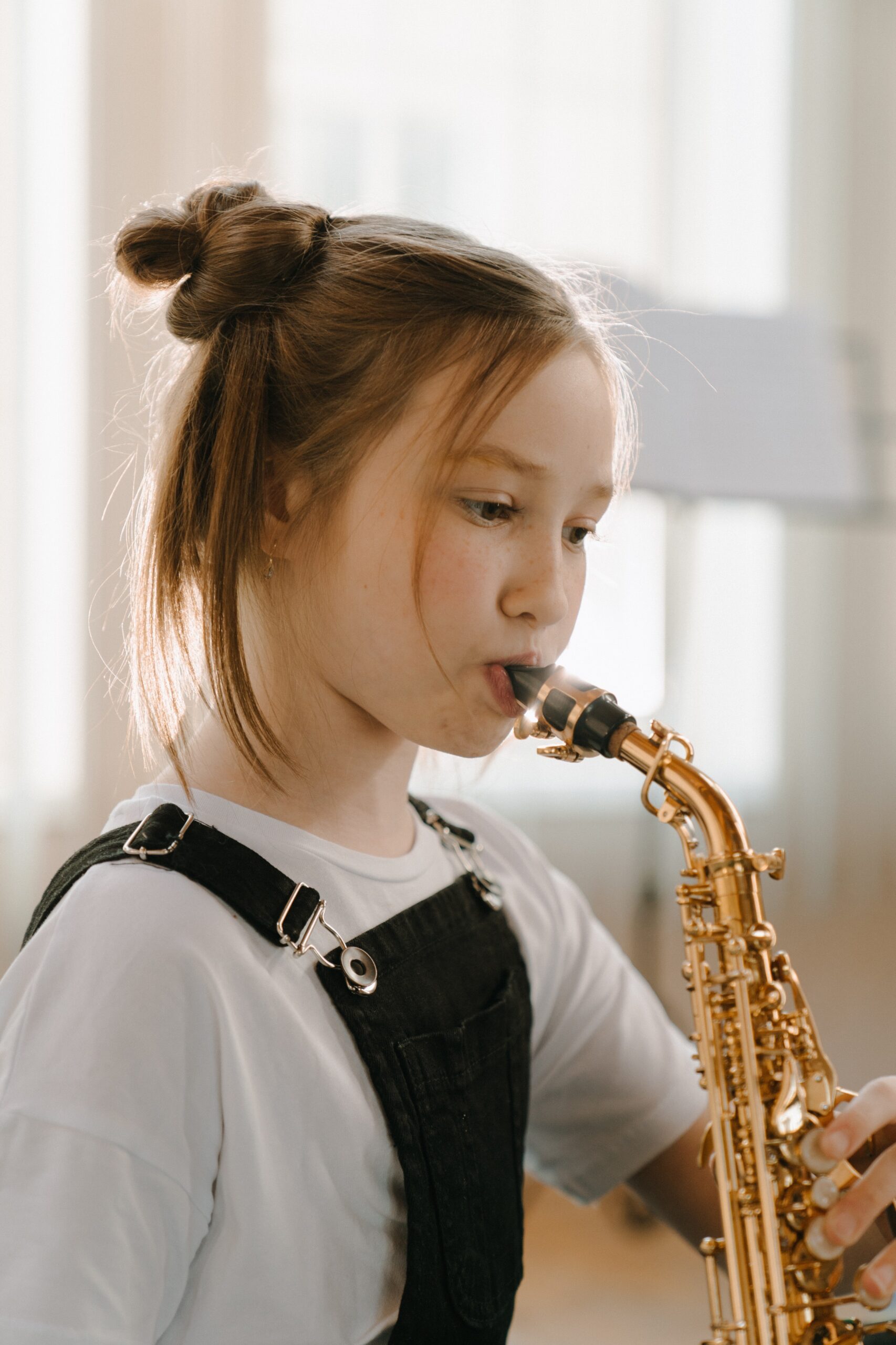 Little white girl practices on her saxophone for a music performance.